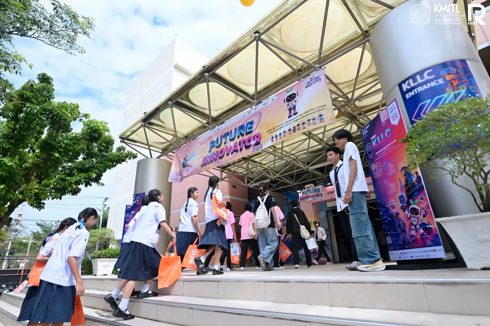 กลุ่มผู้เข้าชมงาน Expo ในชุดนักเรียนเดินขึ้นบันไดใต้ป้าย Future Innovator ที่ทางเข้า KLLC