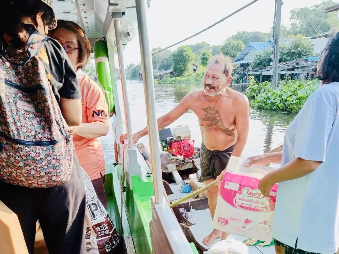 ชาวบ้านรับถุงสิ่งของที่ส่งมอบจากเรือ