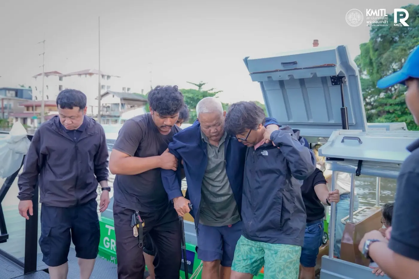 เจ้าหน้าที่ช่วยชายสูงอายุข้างเรือสีเขียว