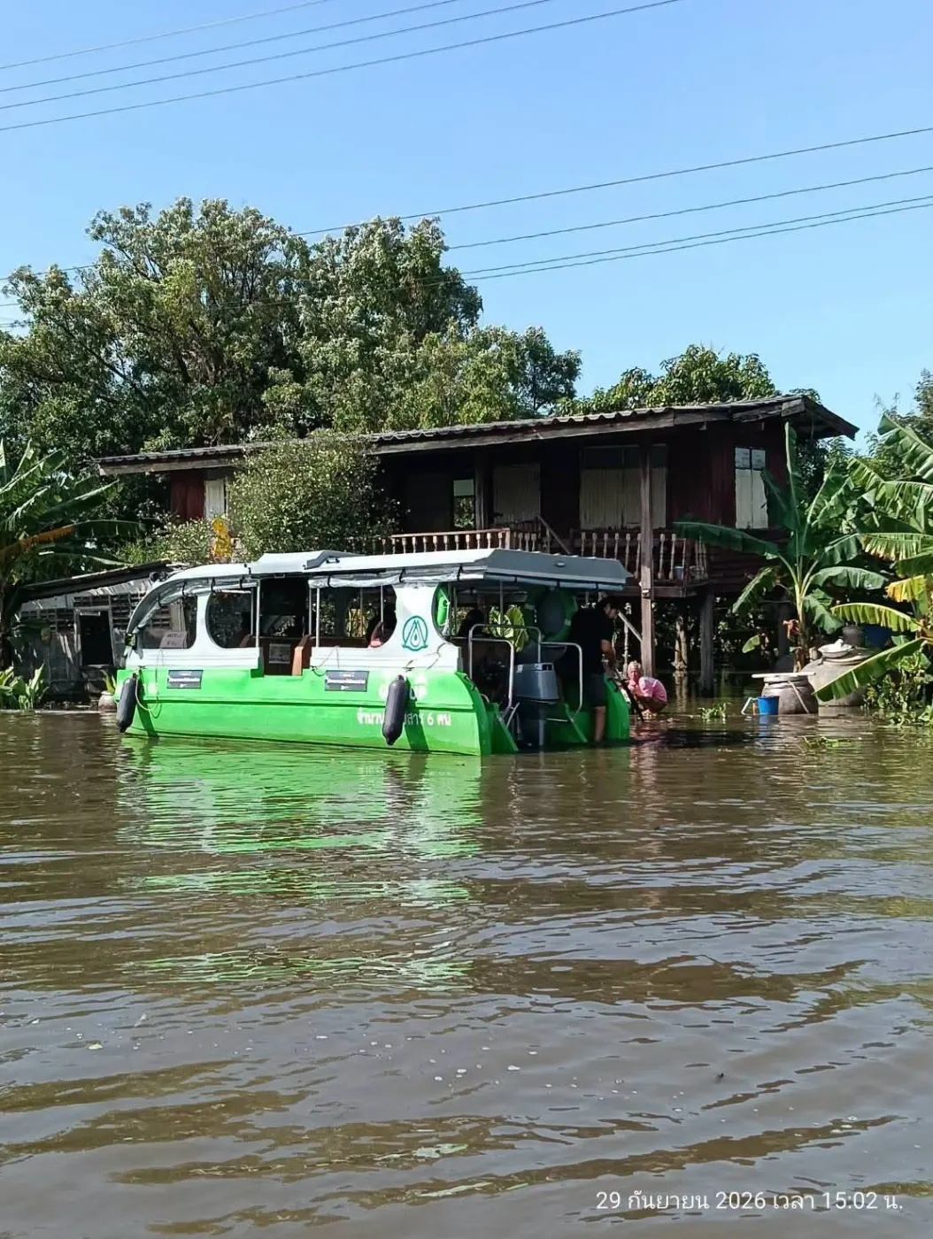 เรือสีเขียวข้างบ้านไม้ที่น้ำท่วม