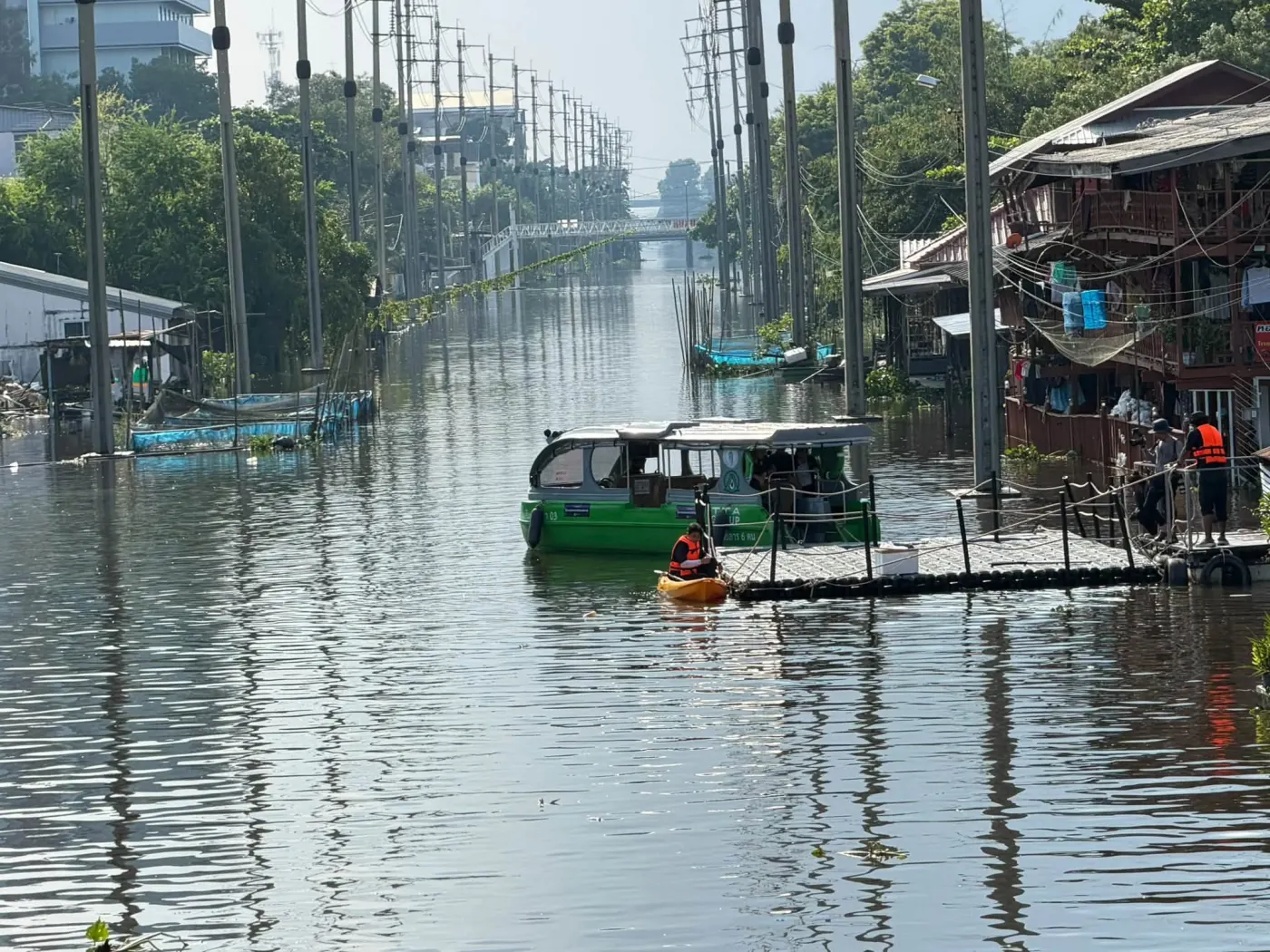 เรือและแพบนถนนยาวที่น้ำท่วม สองข้างมีเสาไฟเรียงราย
