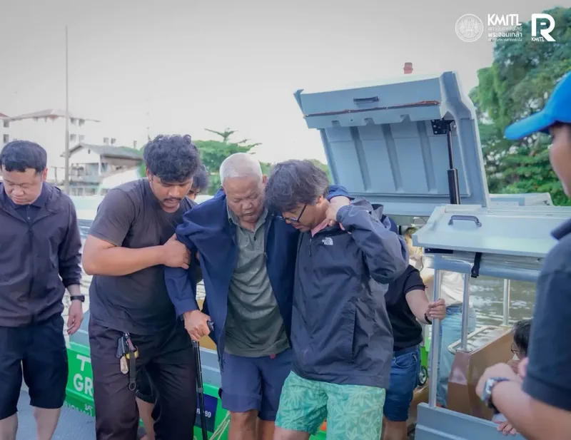 เจ้าหน้าที่ช่วยพยุงผู้สูงอายุลงจากเรือในช่วงน้ำท่วม